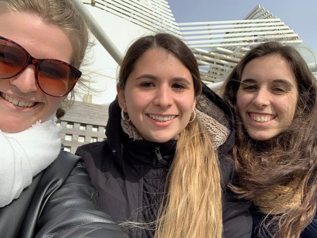 three women smile and pose for a photo on a ship
